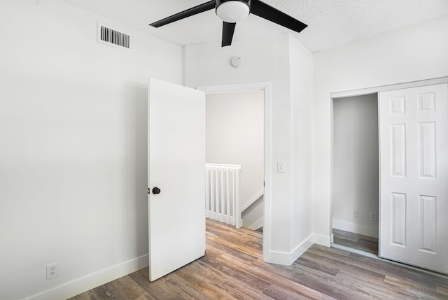 unfurnished bedroom with ceiling fan, hardwood / wood-style floors, and a textured ceiling