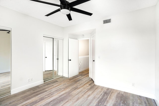 unfurnished bedroom featuring ceiling fan, a textured ceiling, a closet, and light hardwood / wood-style floors