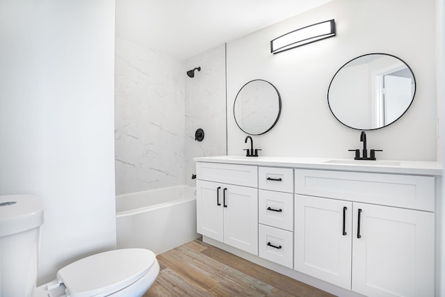 full bathroom with hardwood / wood-style floors, vanity, tiled shower / bath combo, and toilet