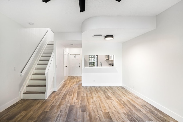 unfurnished living room featuring wood-type flooring, a textured ceiling, and sink