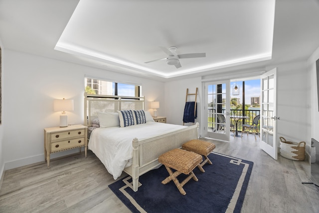 bedroom with french doors, a raised ceiling, light hardwood / wood-style floors, and ceiling fan