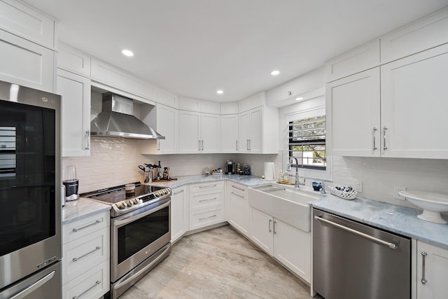 kitchen with appliances with stainless steel finishes, wall chimney exhaust hood, and white cabinetry