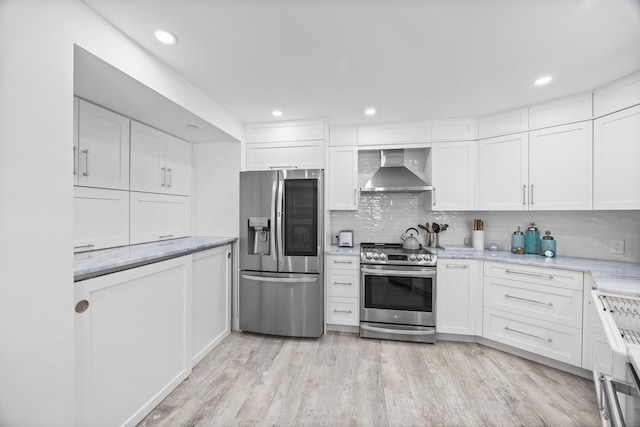 kitchen with light hardwood / wood-style floors, wall chimney exhaust hood, stainless steel appliances, and white cabinets