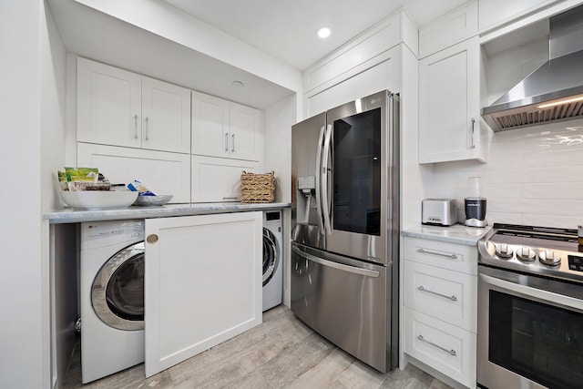 kitchen featuring washer / dryer, white cabinets, wall chimney exhaust hood, light hardwood / wood-style flooring, and appliances with stainless steel finishes