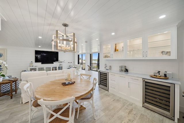 dining space featuring an inviting chandelier, light hardwood / wood-style floors, beverage cooler, and wooden ceiling