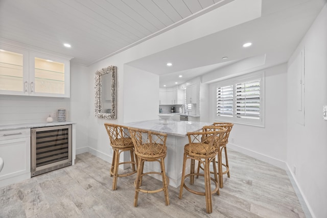 dining room featuring ornamental molding, indoor bar, beverage cooler, wooden ceiling, and light wood-type flooring