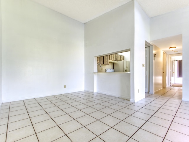 interior space featuring a textured ceiling, light tile patterned floors, and a high ceiling