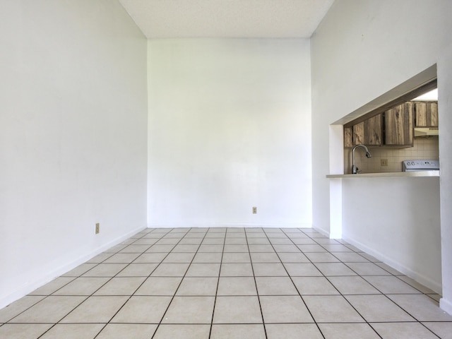 unfurnished room with a textured ceiling, light tile patterned flooring, and sink