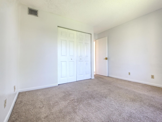 unfurnished bedroom with a textured ceiling, carpet, and a closet