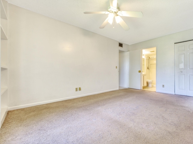 unfurnished bedroom featuring carpet, ceiling fan, ensuite bathroom, and a closet