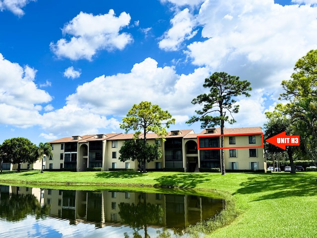 rear view of property featuring a lawn, a water view, and a balcony