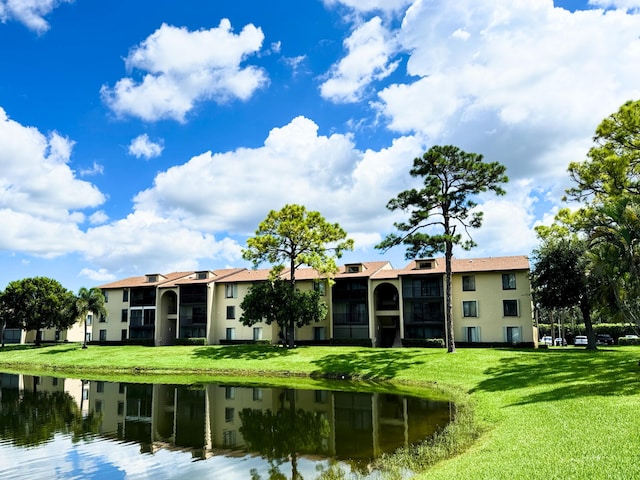 rear view of property with a lawn, a water view, and a balcony