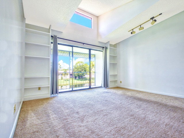 unfurnished room featuring a textured ceiling, rail lighting, built in features, and light colored carpet