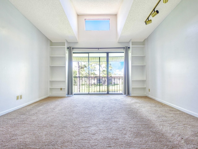 carpeted spare room with a textured ceiling, track lighting, and high vaulted ceiling