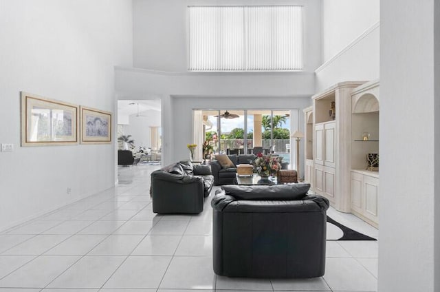 tiled living room featuring ceiling fan, built in features, and a high ceiling