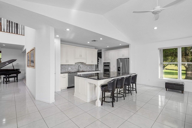 kitchen with a kitchen island, a breakfast bar area, white cabinets, light tile patterned floors, and stainless steel appliances