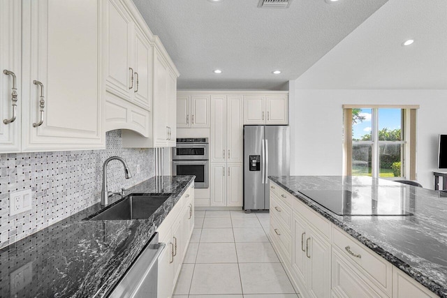 kitchen featuring white cabinetry, stainless steel appliances, sink, and dark stone countertops