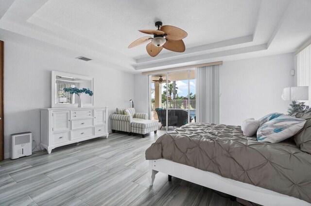 bedroom with a raised ceiling, access to exterior, and ceiling fan