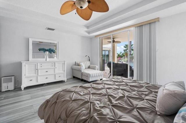 bedroom with access to outside, light hardwood / wood-style floors, a raised ceiling, and ceiling fan