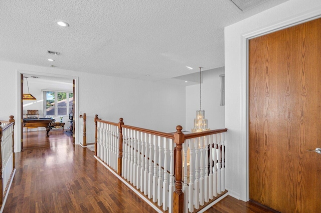 hallway with dark hardwood / wood-style flooring, a chandelier, and a textured ceiling