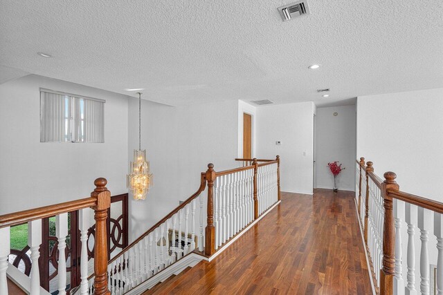 hall featuring an inviting chandelier, a textured ceiling, and dark hardwood / wood-style flooring