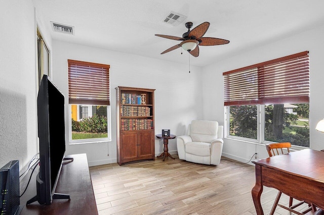 living area with a healthy amount of sunlight, ceiling fan, and light hardwood / wood-style flooring