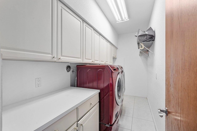 washroom featuring cabinets, washing machine and dryer, and light tile patterned floors