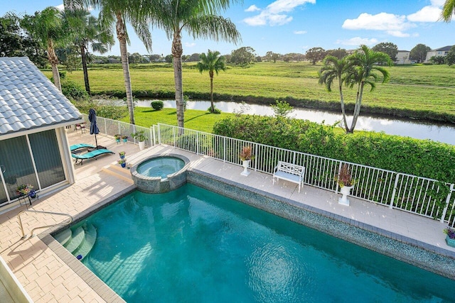 view of pool featuring an in ground hot tub, a water view, and a patio area