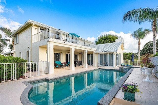 back of property with ceiling fan, a balcony, a fenced in pool, and a patio area