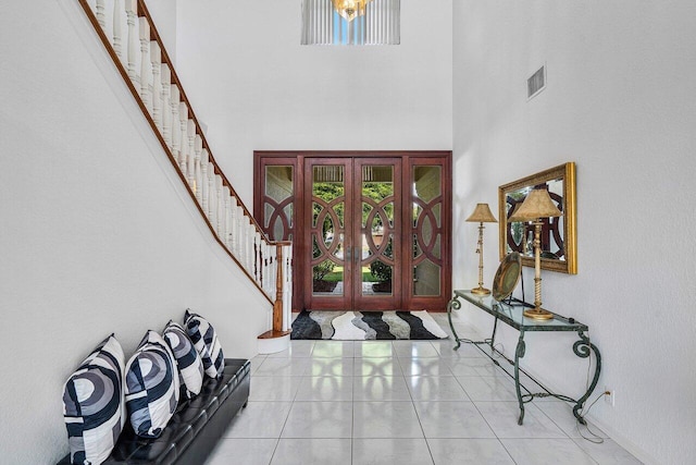 foyer with french doors, a towering ceiling, and light tile patterned floors