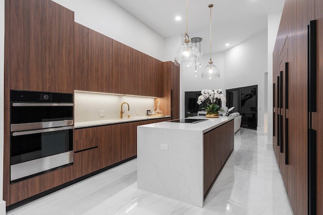 kitchen with sink, hanging light fixtures, a kitchen island, a high ceiling, and double oven