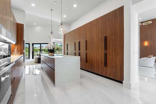 kitchen featuring pendant lighting, a center island, sink, stainless steel double oven, and a high ceiling