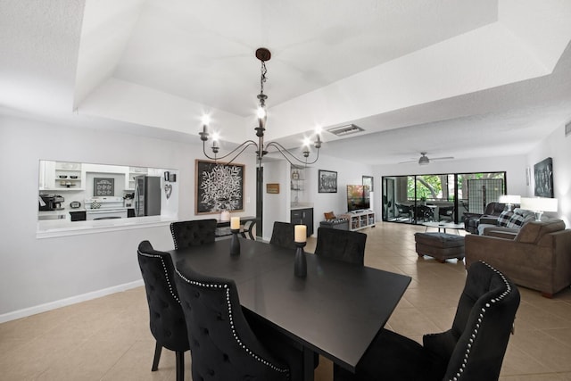 dining room featuring a textured ceiling, ceiling fan with notable chandelier, a tray ceiling, and light tile patterned floors