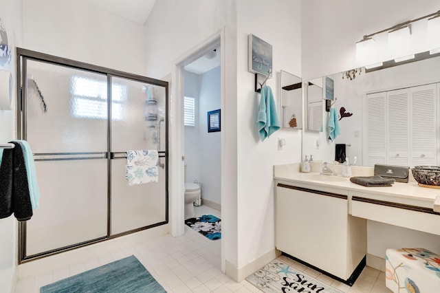 bathroom with vanity, a shower with door, tile patterned floors, and toilet