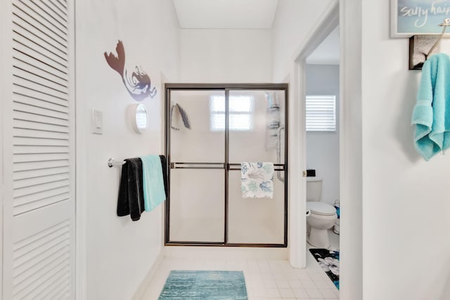 bathroom featuring tile patterned floors, toilet, and a shower with door