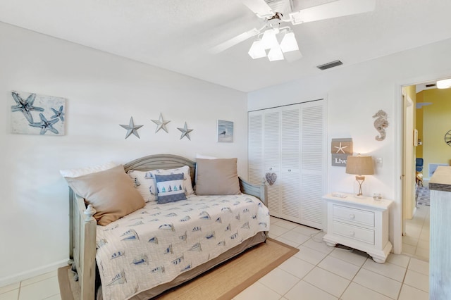 bedroom with a closet, light tile patterned floors, and ceiling fan