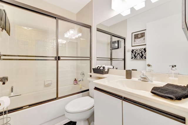 full bathroom featuring vanity, combined bath / shower with glass door, and toilet