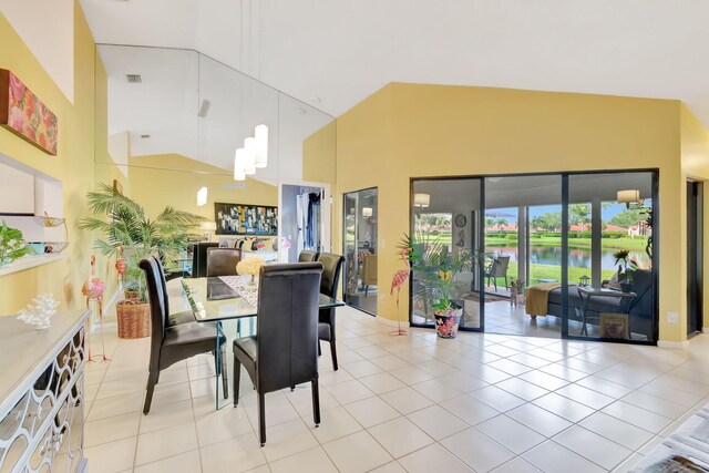 tiled dining space featuring high vaulted ceiling and a water view