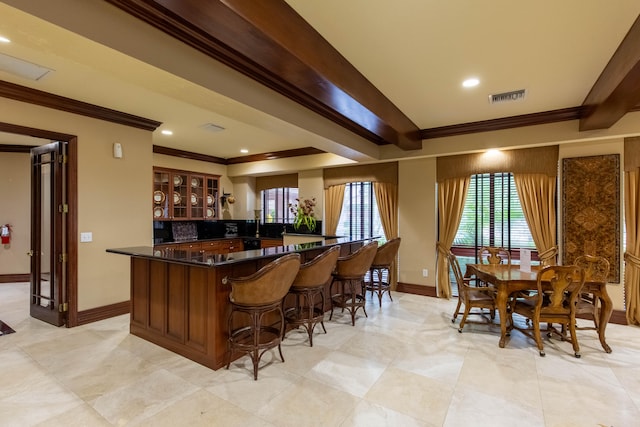 kitchen featuring kitchen peninsula, ornamental molding, and a breakfast bar area