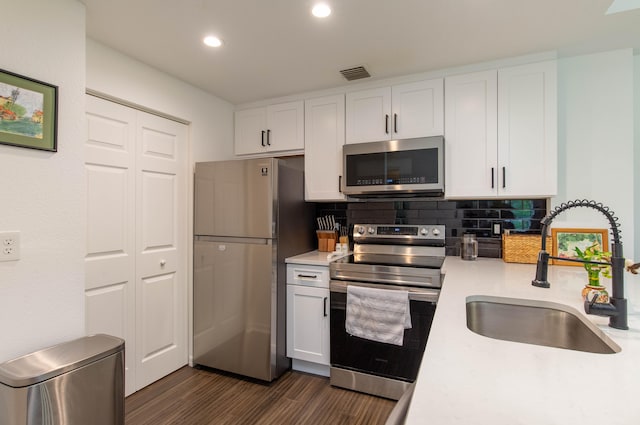 kitchen featuring dark hardwood / wood-style floors, sink, white cabinets, decorative backsplash, and stainless steel appliances