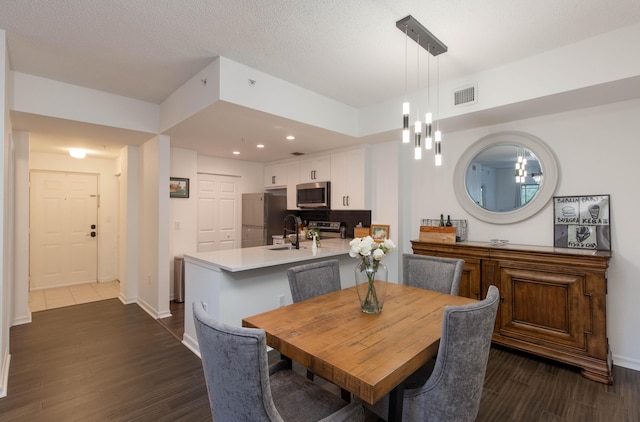 dining space featuring a textured ceiling, dark hardwood / wood-style floors, and a notable chandelier