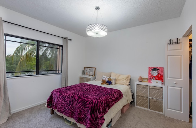 bedroom featuring a textured ceiling and light colored carpet