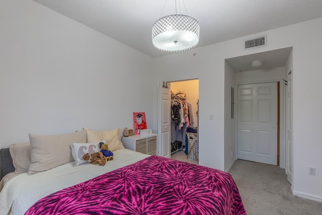 carpeted bedroom featuring a closet, a walk in closet, and a textured ceiling