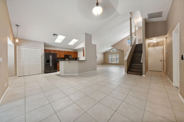 unfurnished living room with light tile patterned floors and vaulted ceiling with skylight