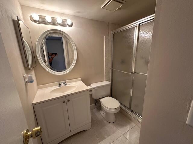 bathroom featuring vanity, a shower with shower door, toilet, and tile patterned floors