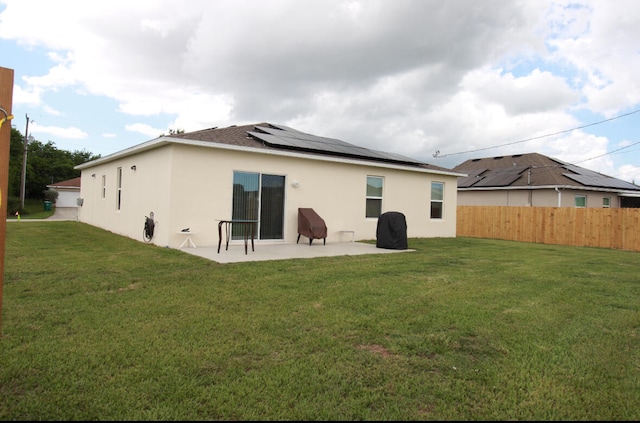 back of house featuring solar panels, a yard, and a patio area