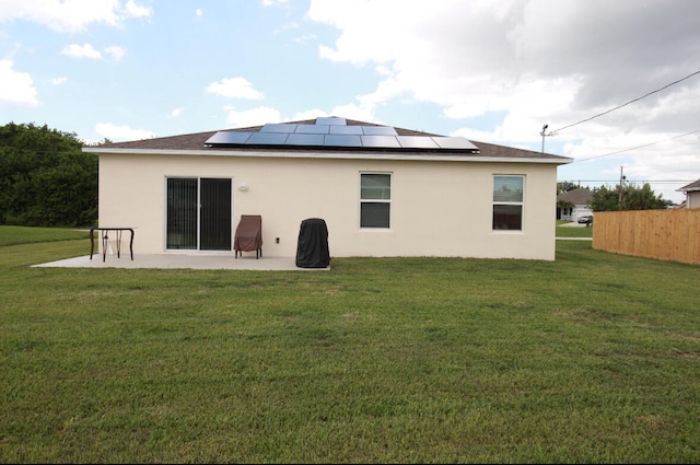 back of house featuring a patio area, solar panels, and a yard