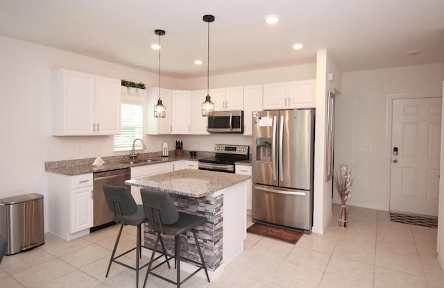 kitchen featuring a kitchen breakfast bar, white cabinets, a kitchen island, stainless steel appliances, and sink