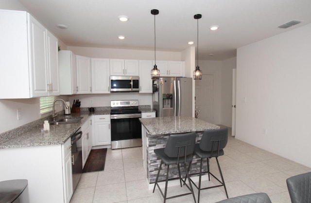 kitchen with sink, stone countertops, a kitchen island, white cabinetry, and appliances with stainless steel finishes