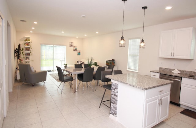 kitchen featuring dark stone countertops, dishwasher, a center island, and white cabinetry